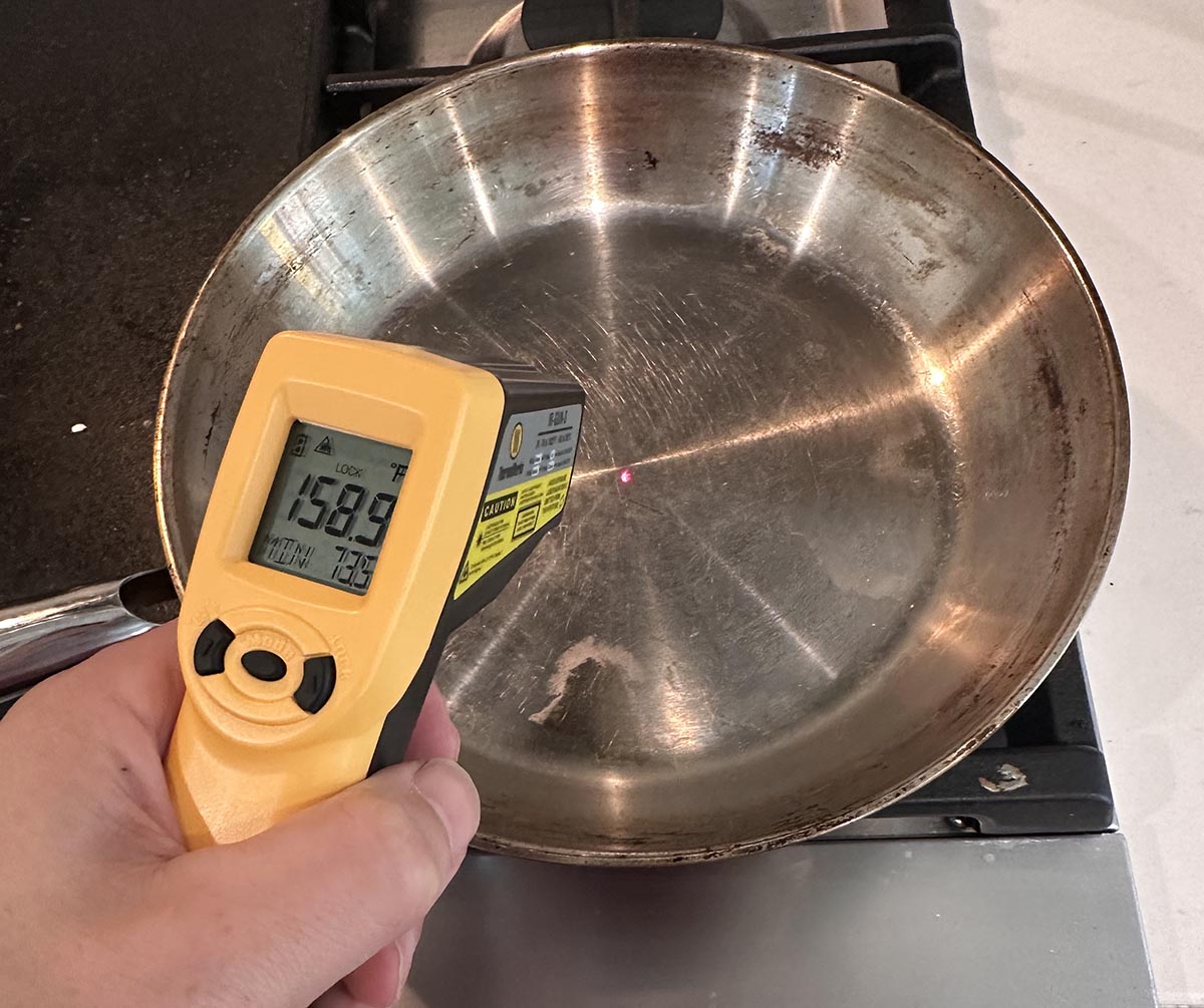 Person using ThermoWorks IR Gun to take surface temperature of stainless steel pan