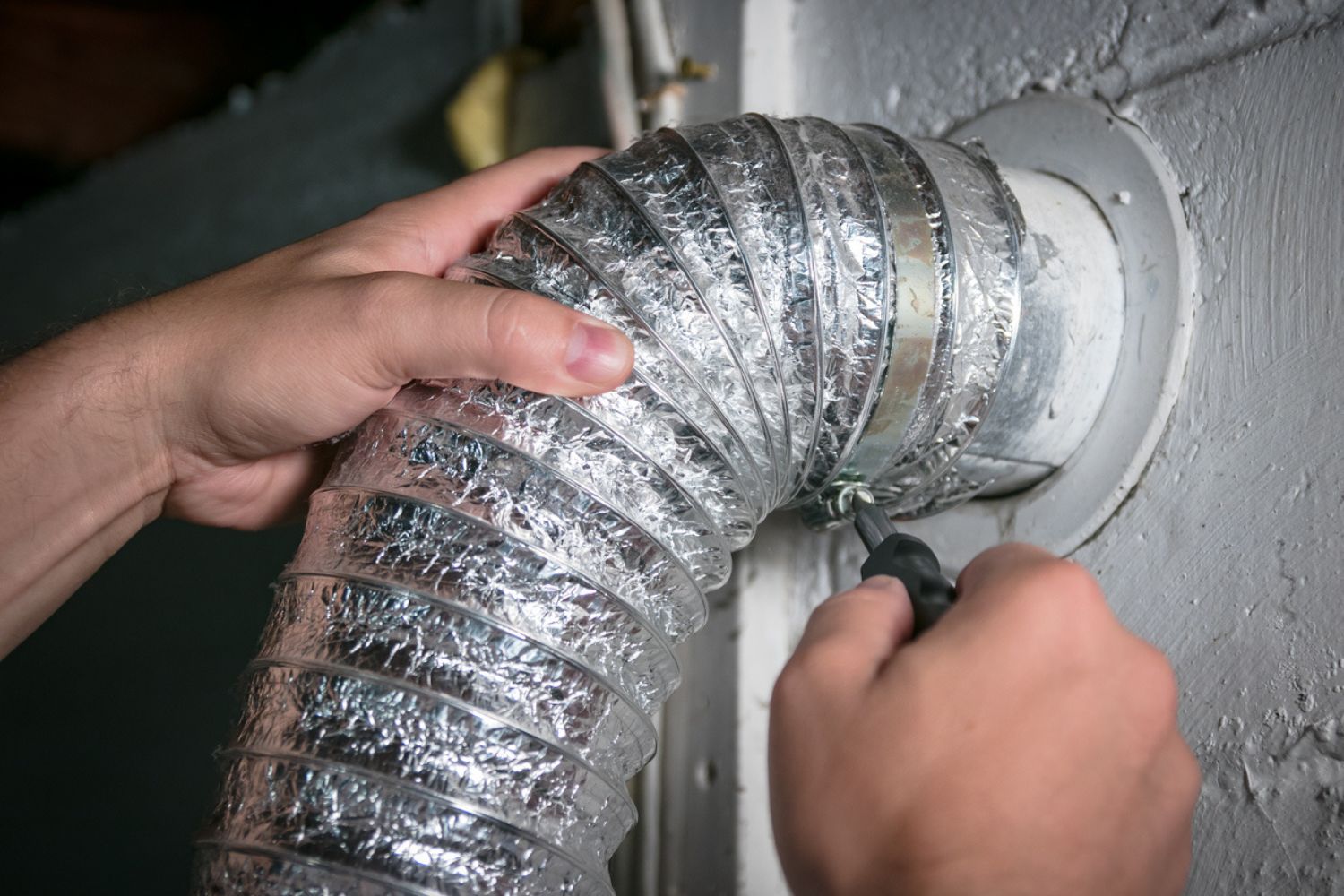 Professional Who Cleans Dryer Vents Replacing a Flexible Dryer Vent Tube from the Wall Vent