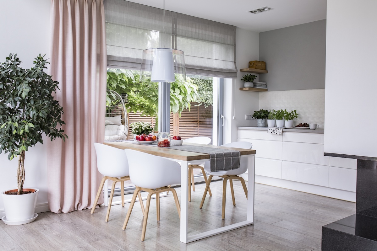 A bright kitchen with sheer roman shades and pink drapes.