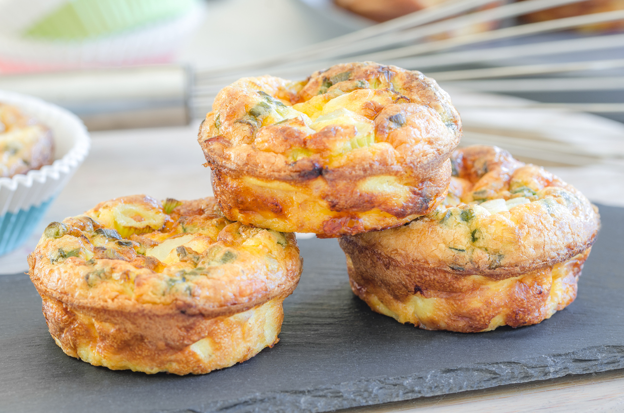 Homemade tartlets filled with ham, cheese , green onions, baked in silicone cups and served on a slate plate for a brunch or breakfast