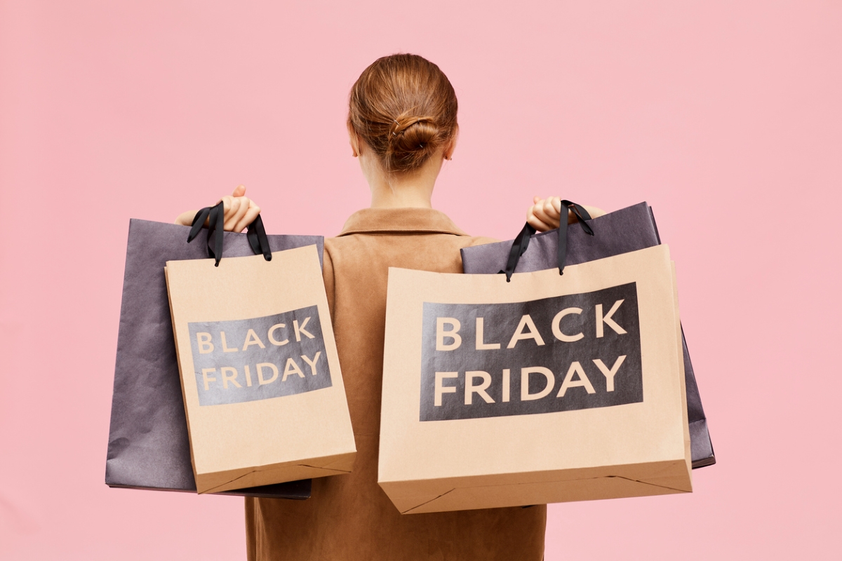 Woman holding Black Friday bags behind her.