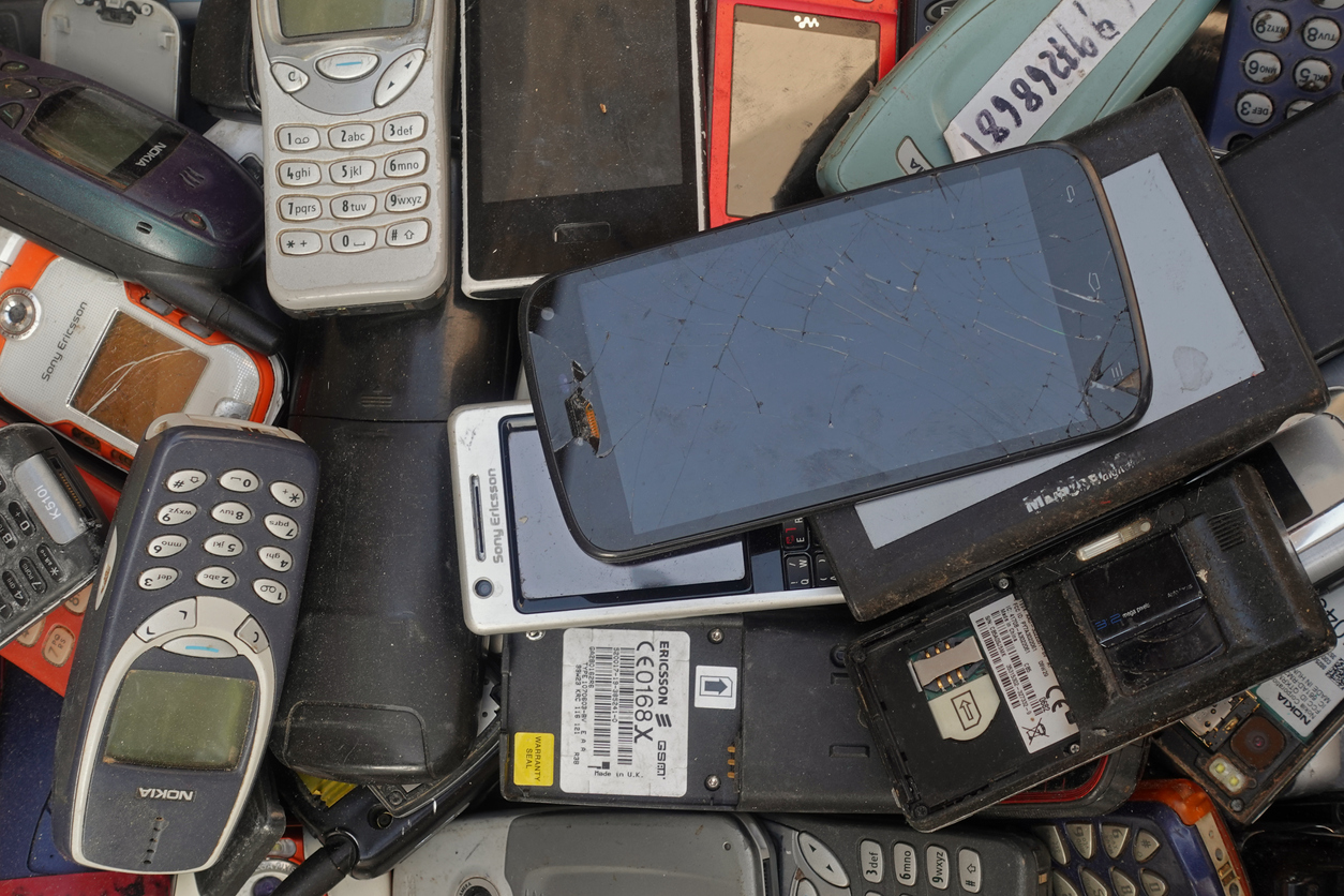 A pile of old cellphones broken smartphones and vintage mobile phones at junk shop.