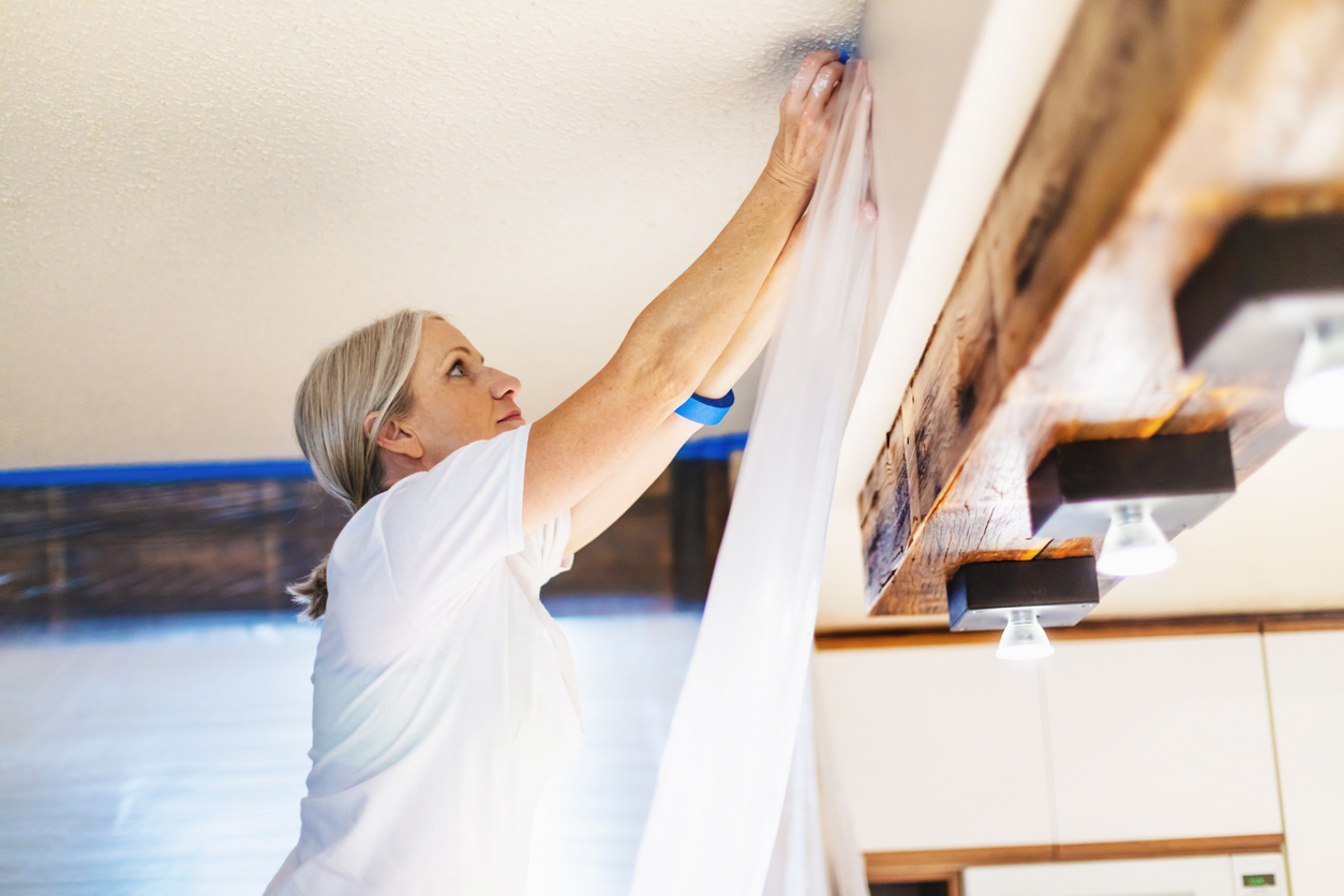 Adult Female Using Painter's Tape and Plastic for Painting Preparation; Private Residence Remodel.