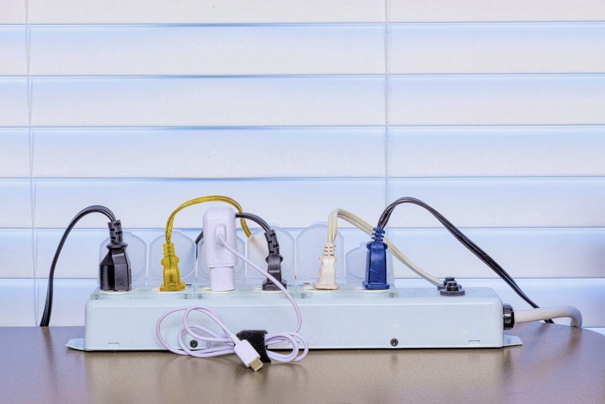 A home office power strip filled with plugged in electronic devices.