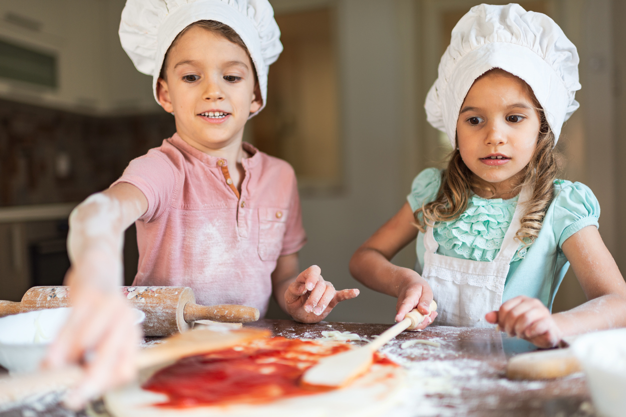 Toddler boy and girl are preparing food in kitchen.
