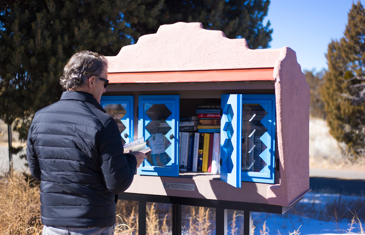 Santa Fe, NM: A man browses at a Little Free Library constructed in traditional Santa Fe architectural style.