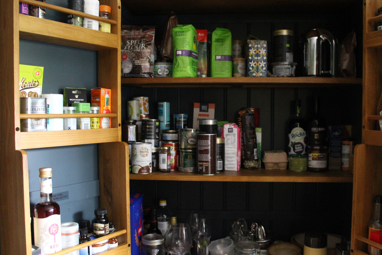 An open pantry cabinet with shelves of spices and other packaged dried food.