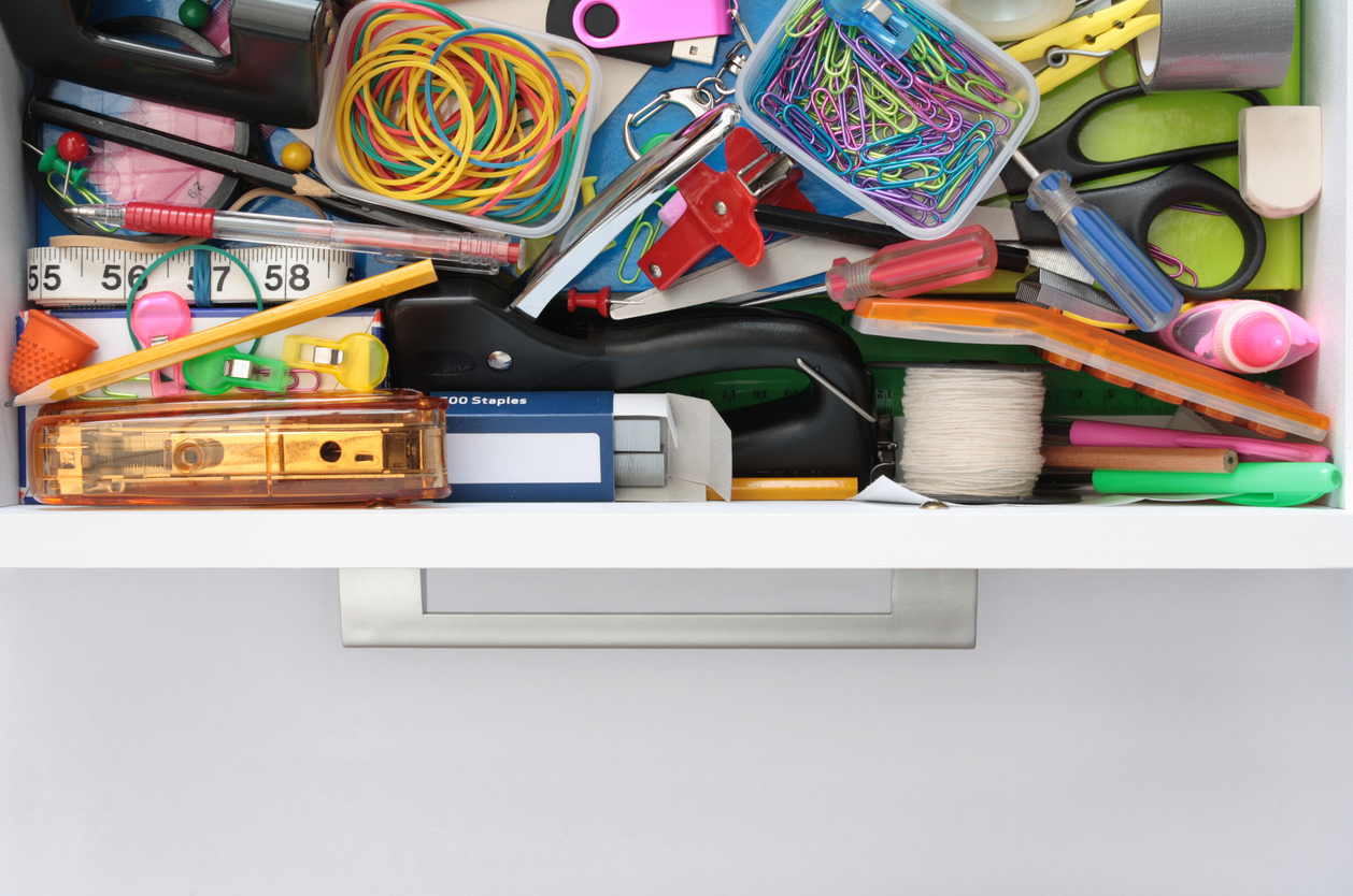 A-drawer-is-pulled-out-to-reveal-a-mess-of-assorted-office-supplies-and-craft-supplies.