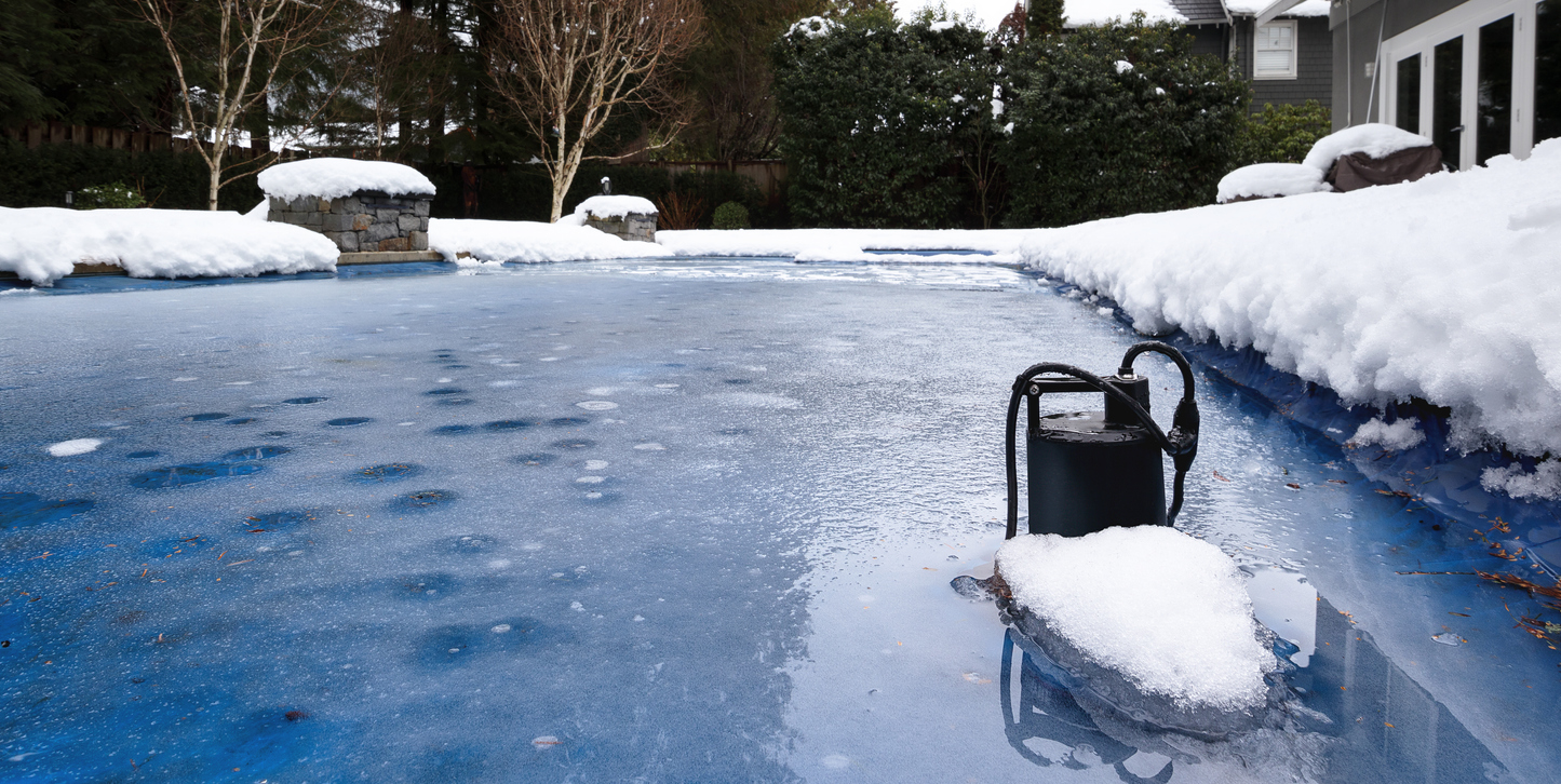 A-pool-pump-is-covered-in-snow-and-ice-on-the-edge-of-a-frozen-swimming-pool.