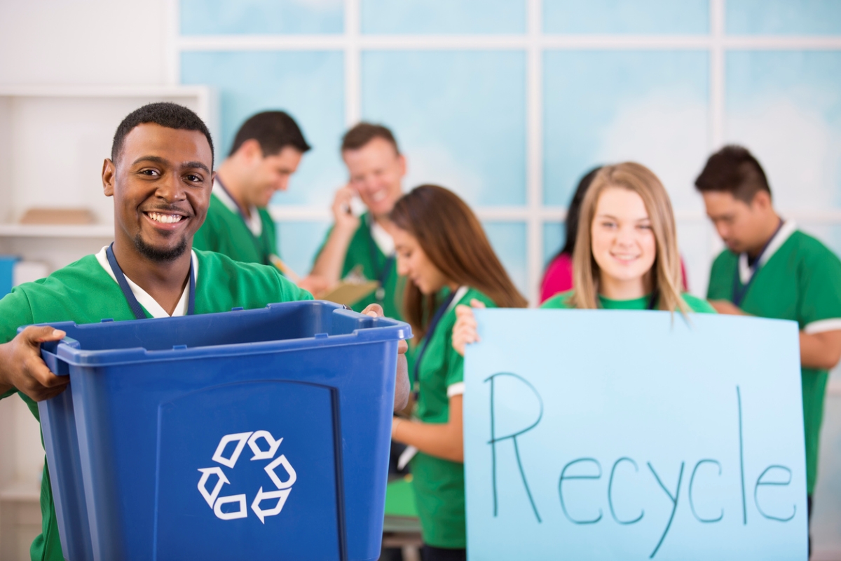 Volunteers holding recycling bin and sign.