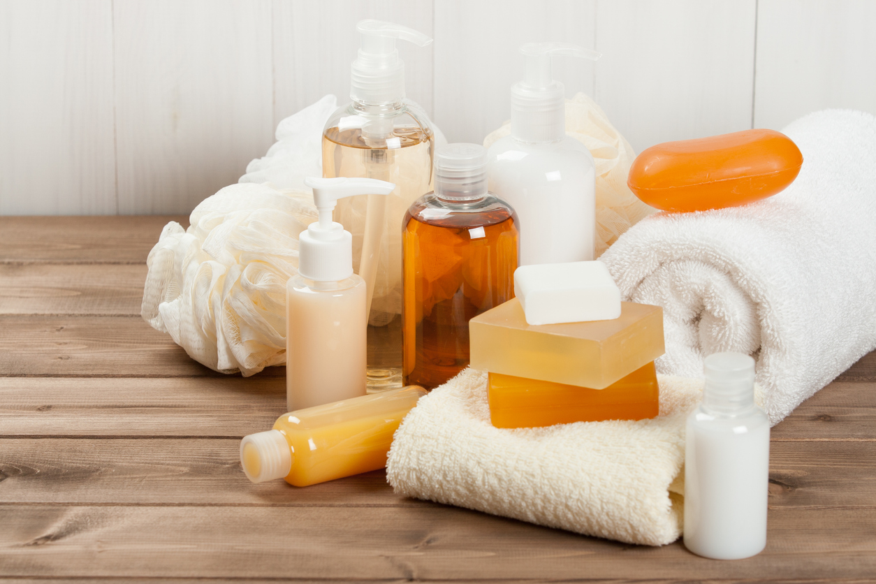 A collection of toiletries including bars of soap and bottles gathered with towels on bathroom counter.