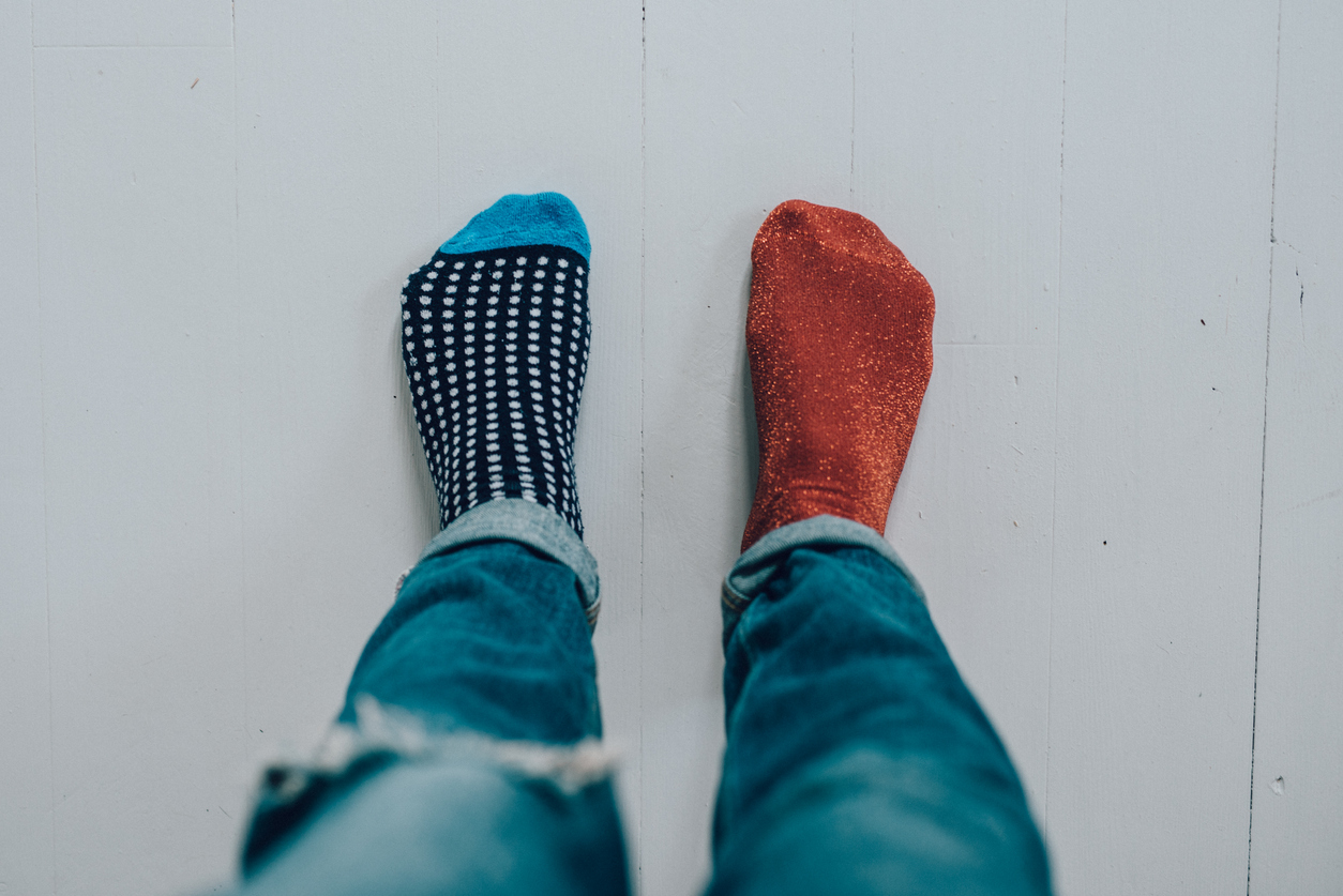 Point of view shot of a person's feet wearing jeans and two different socks.
