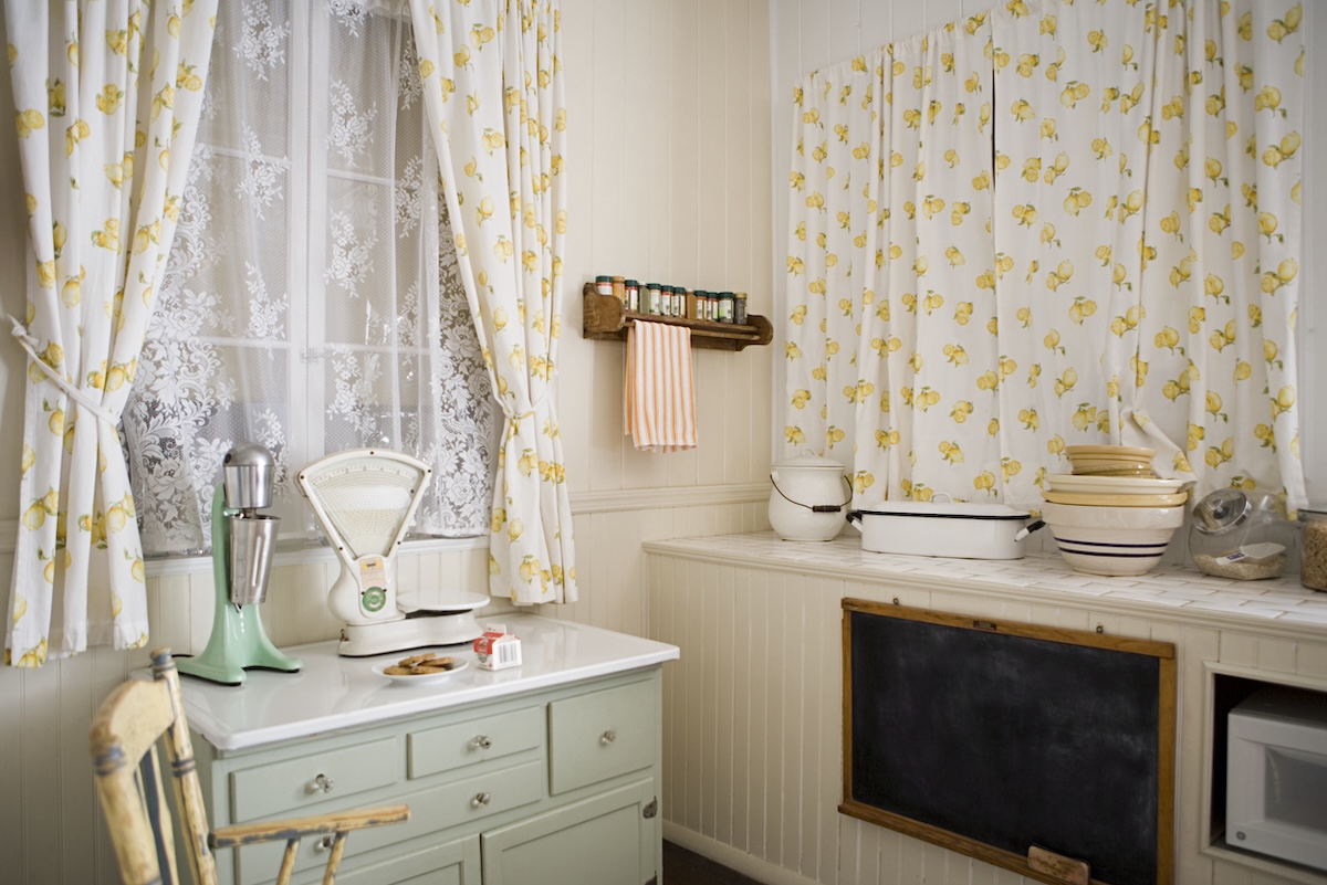 A small cottage kitchen with yellow curtains.
