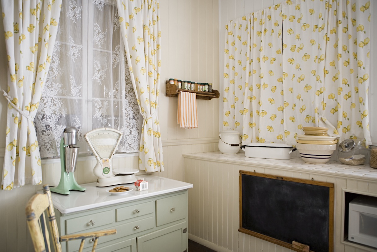 A small cottage kitchen with yellow curtains.