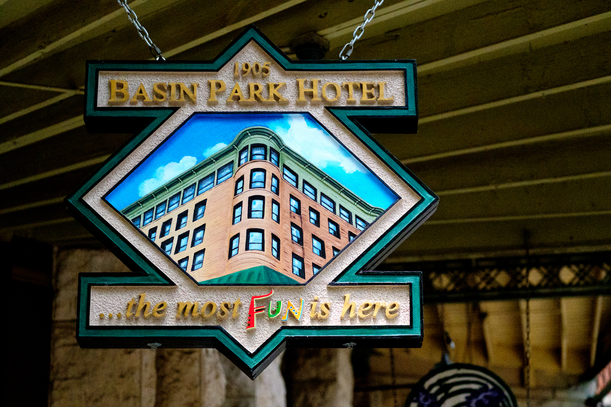 Hand-carved wooden sign for the Basin Park Hotel, a historic building in the middle of downtown Eureka Springs, Arkansas. The sign is hanging above the sidewalk.