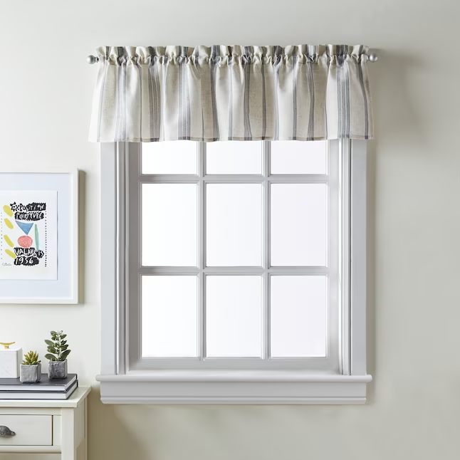 A white valance covering the top of a small kitchen window.