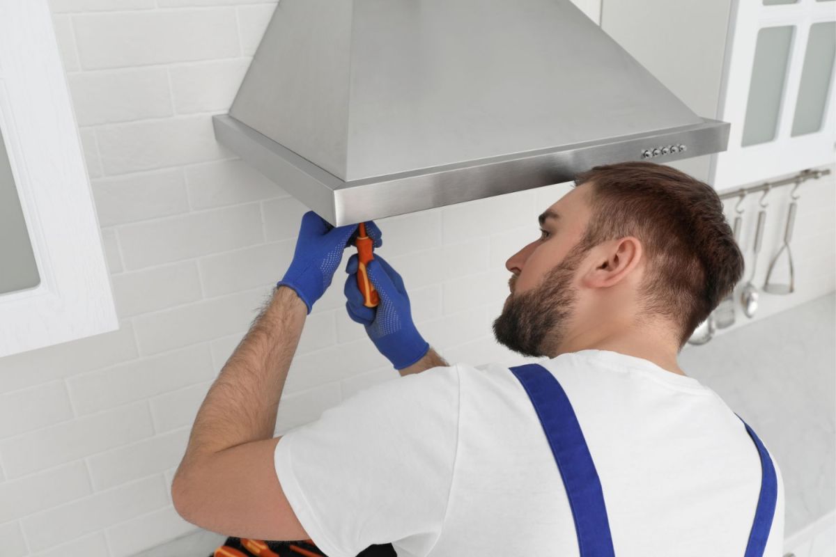 How Much Does Range Hood Installation Cost: An expert tradesman connecting the ductwork for a newly installed range hood