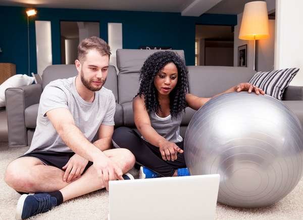 Couple going over home workout routing on laptop