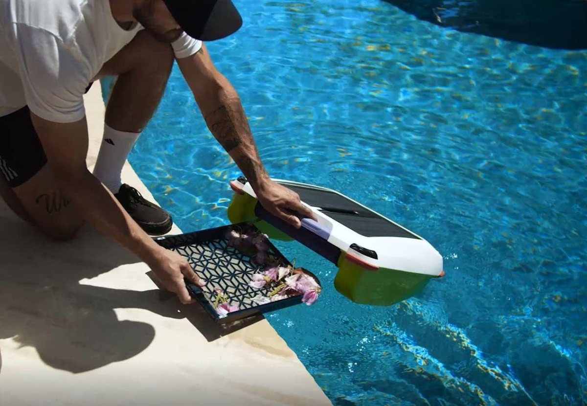 A person by the edge of a pool emptying the mesh filter basket of the Pivot-Solar Breeze Ariel Smart Robot Pool Cleaner.
