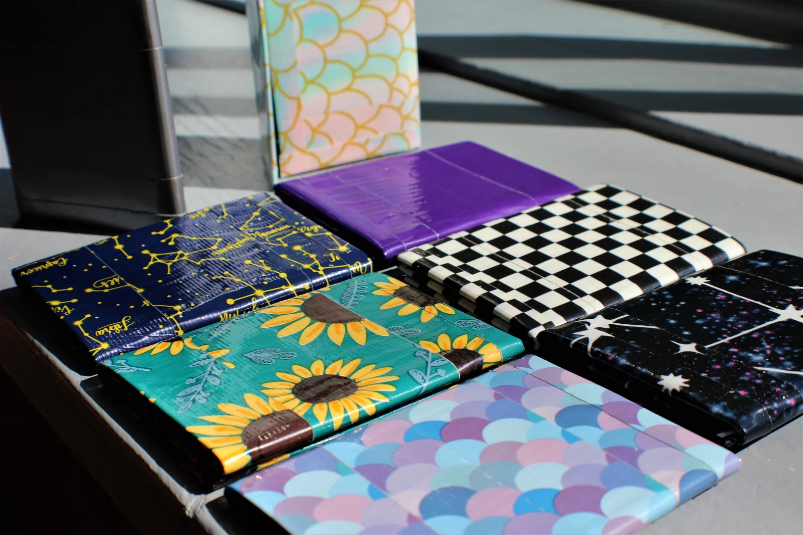 Colorful patterned duct tape wallets sit side by side on a table.