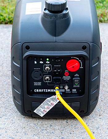 A yellow extension cord plugged into one of the ports on the Craftsman 3000-Watt Inverter Generator with several other ports still open.
