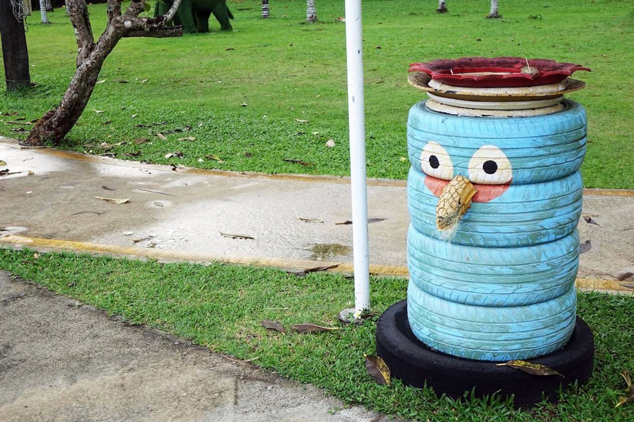 A trash can made from old tires with a face painted on it in a park