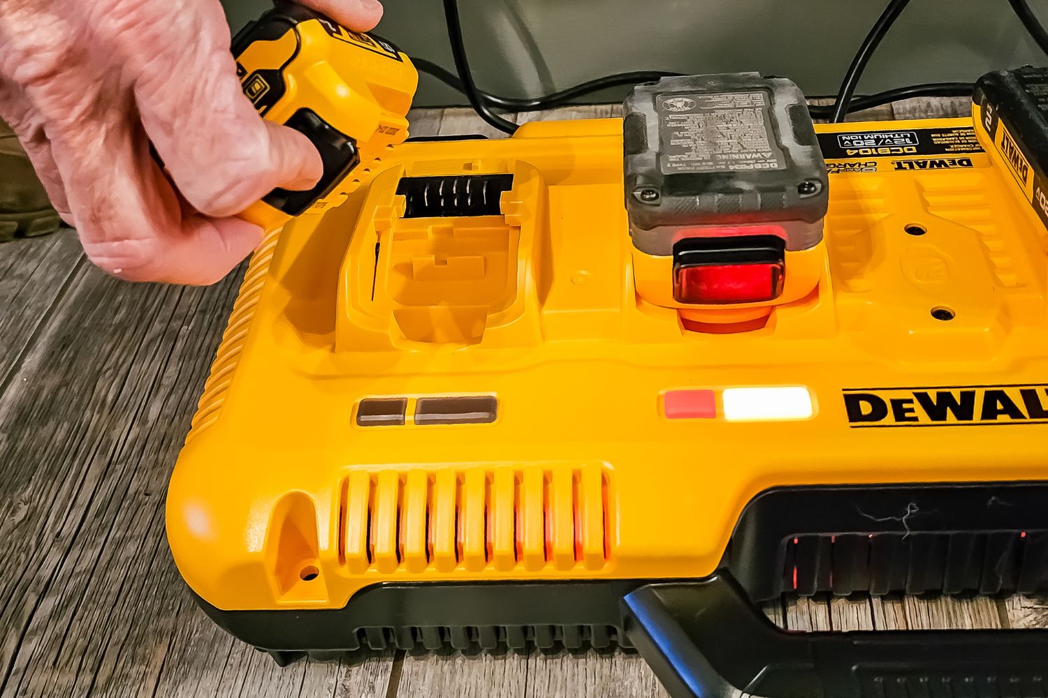 A person removing a charged battery from the DeWalt charging station.
