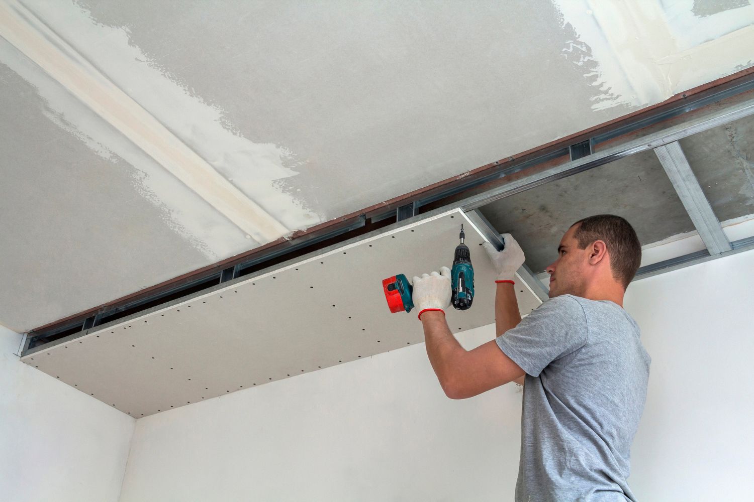 Estimating Drop Ceiling Cost: Young Man Installing Drywall