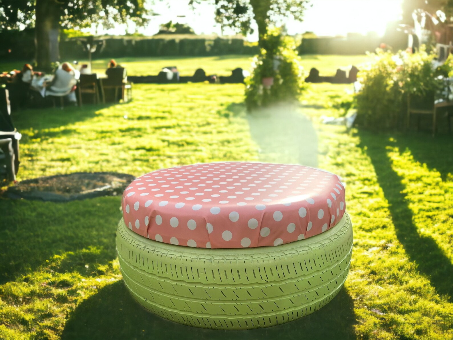 A stool made from an old tire painted green with pink polka dot upholstry on top, in a sunny backyard party.