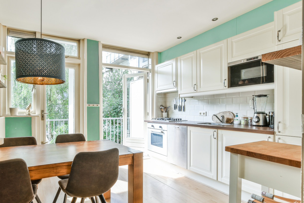A small kitchen and dining room with seafoam green accent wall paint. with