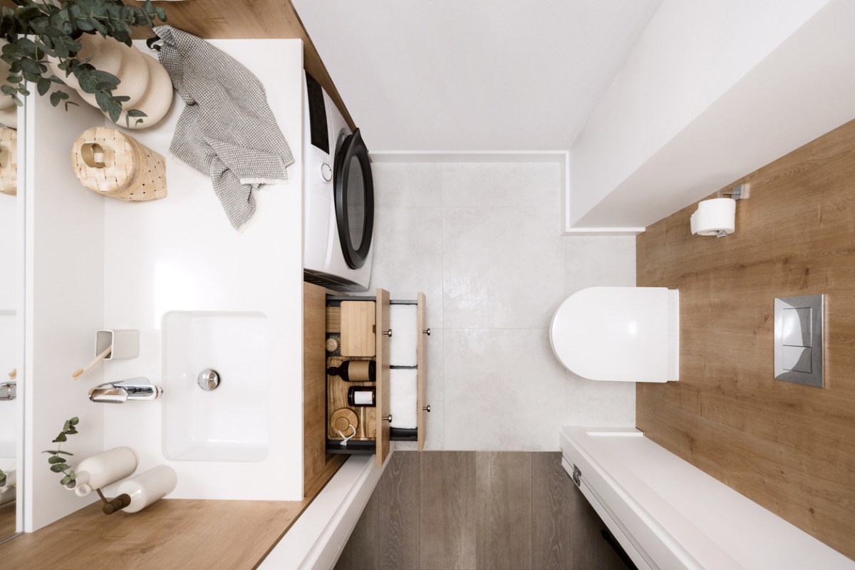 The birds-eye-view of a tiny half-bathroom with white tile, wood accents, and a washer.