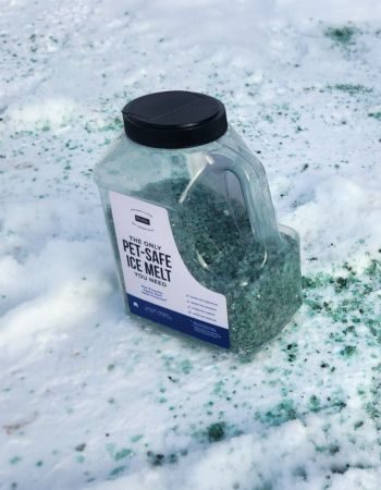 A jug of the Natural Rapport Pet-Safe Ice Melt sitting on icy and snowy cement.