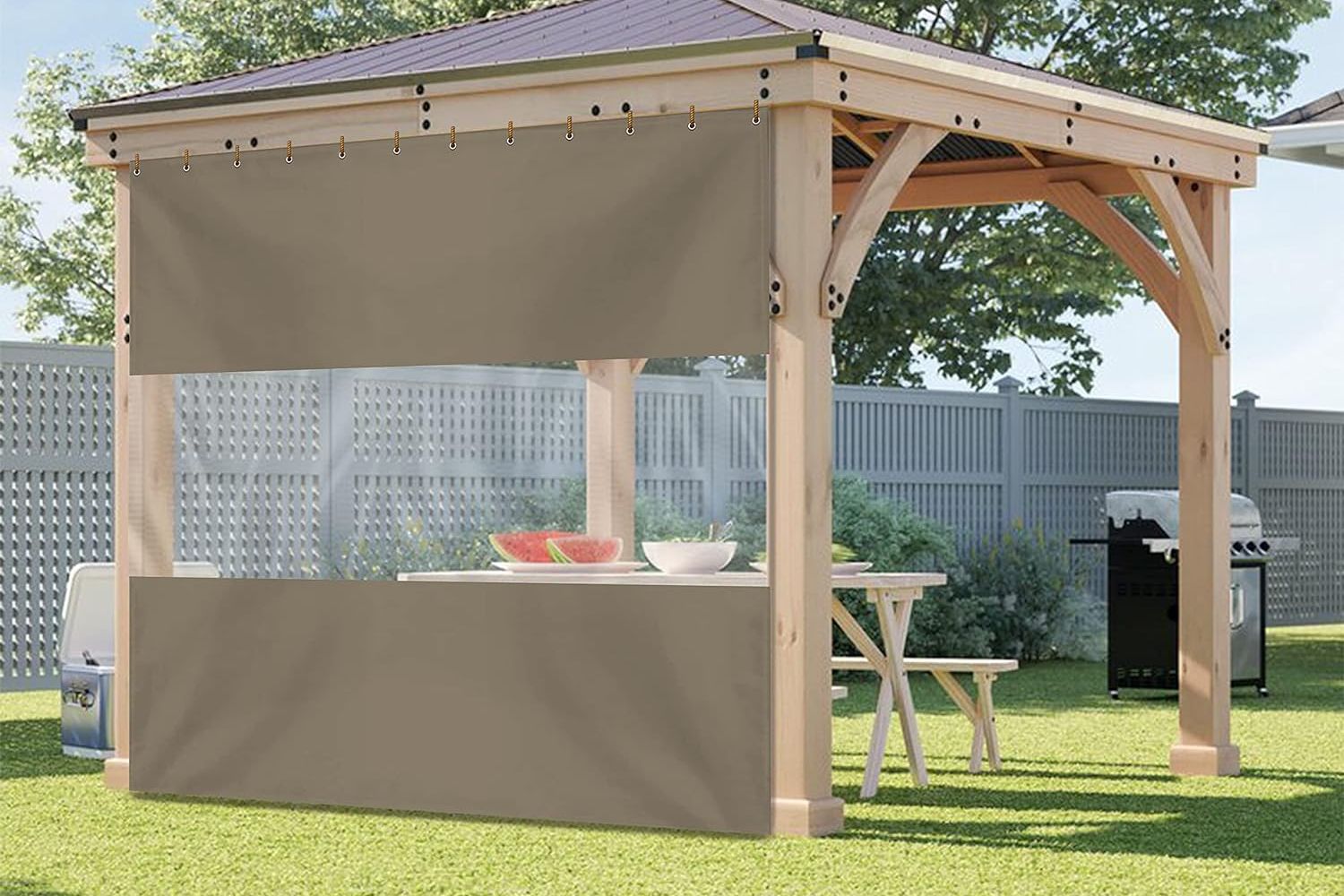 The Best Outdoor Curtains The Covers & All Outdoor Curtain With Clear Vinyl Panel installed along one edge of a pergola to provide privacy and shade for an outdoor picnic table.