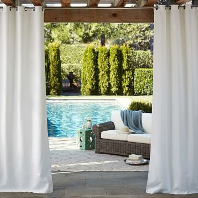  The Sunbrella Solid Outdoor Grommet Curtain installed on a pergola to shade outdoor furniture next to a pool.