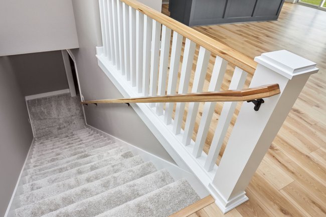 A close up of railings going down grey carpeted stairs.