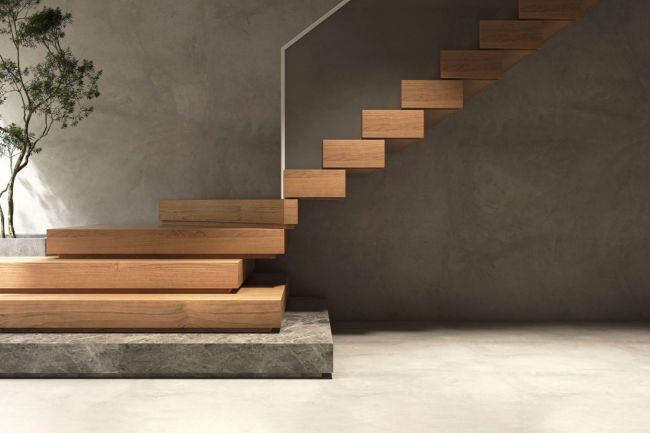 A close up of elegant wooden stairs against a grey wall.