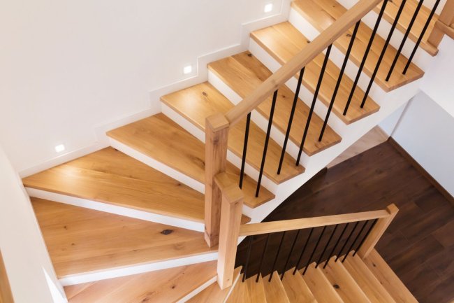 A close up of wooden stairs and wooden railings.