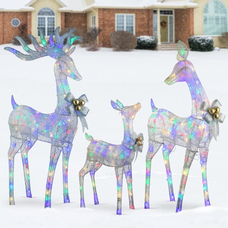 Three-piece deer family outdoor Christmas light decorations in front of a house with snow on the ground.