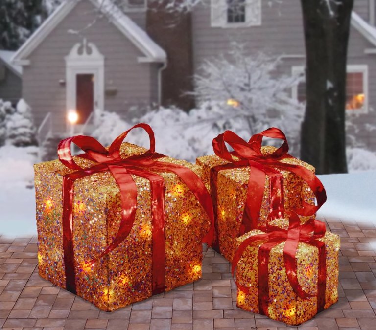Set of three gold gift boxes with red ribbon, outdoor holiday decor.