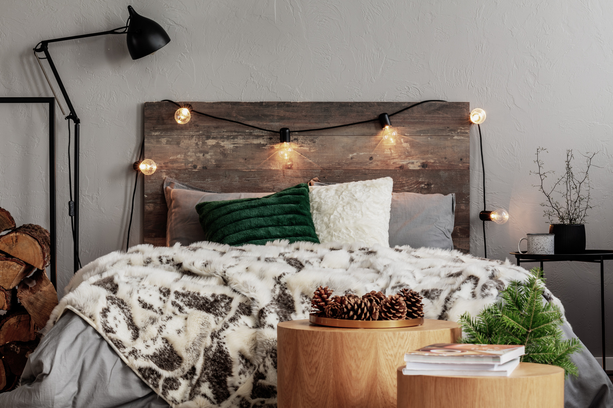 Pine-cones-and-greenery-combine-with-various-wood-tones-to-create-a-rustic-style-in-a-bedroom-with-faux-fur-bedding.