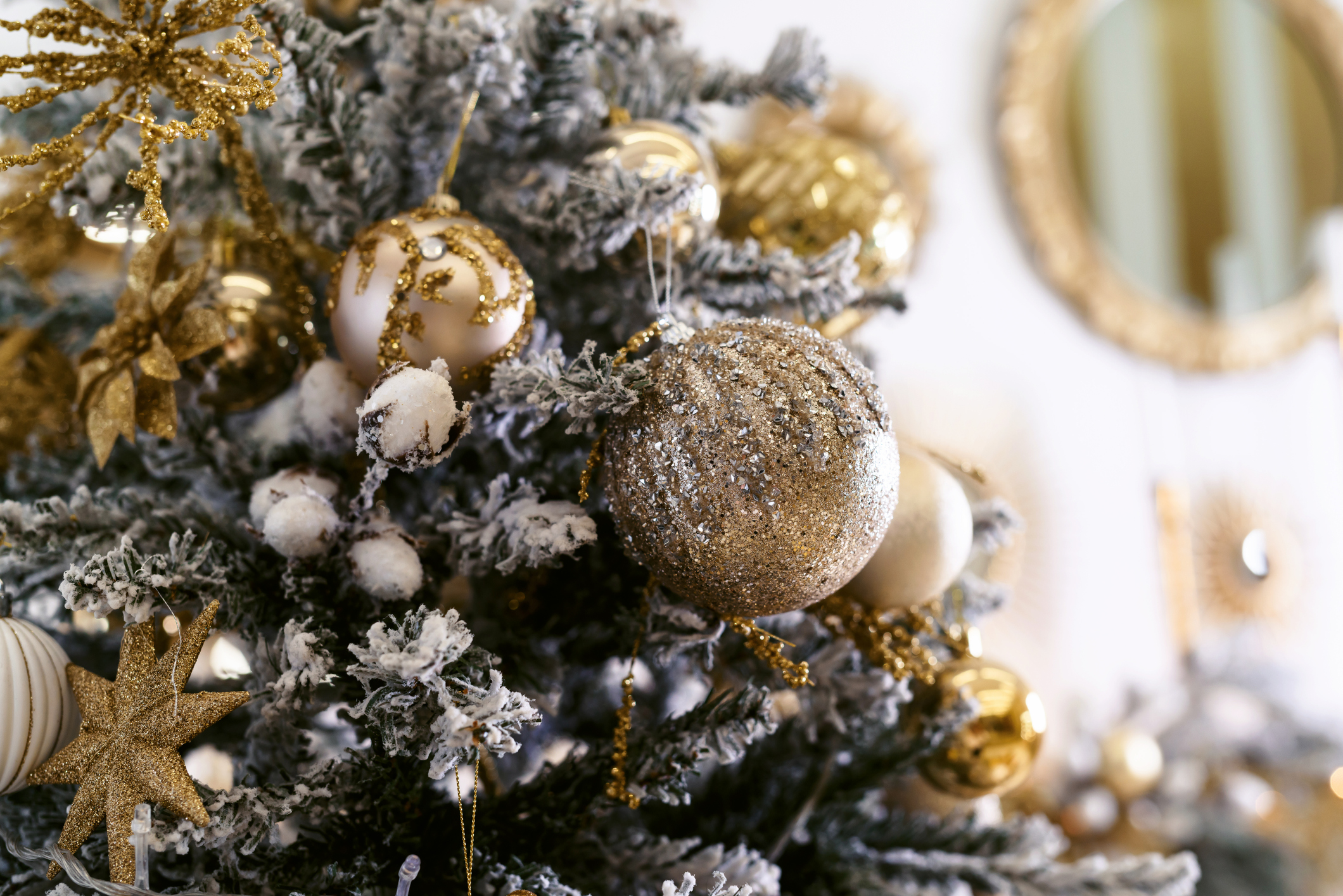 close view of Christmas tree with gold ornaments and frosted branches