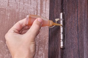 A-hand-drops-oil-from-a-small-dropper-onto-a-door-hinge.