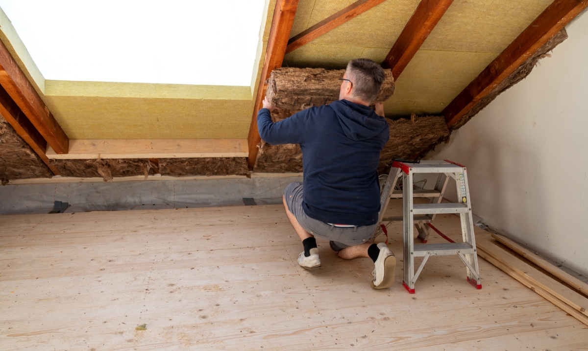Person adding attic insulation.