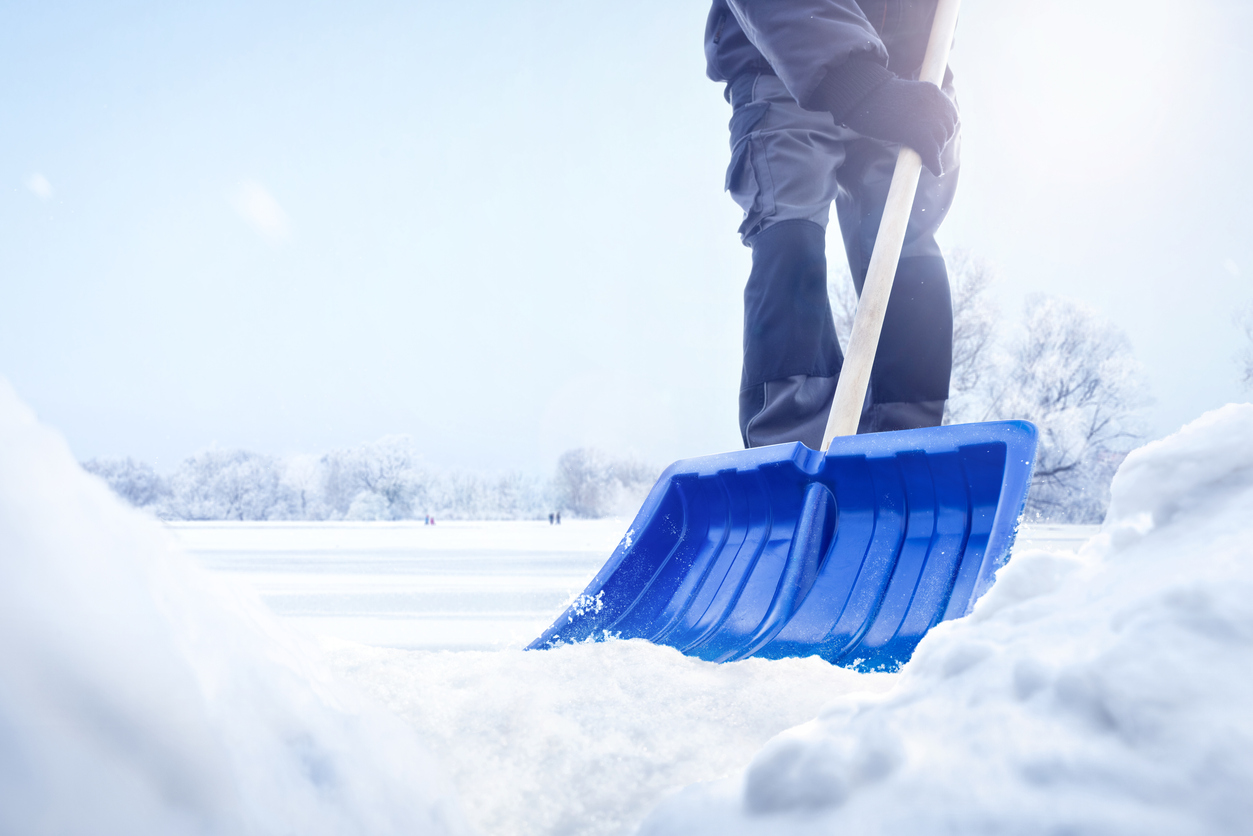 A-person-uses-a-blue-shovel-to-sweep-away-snow.
