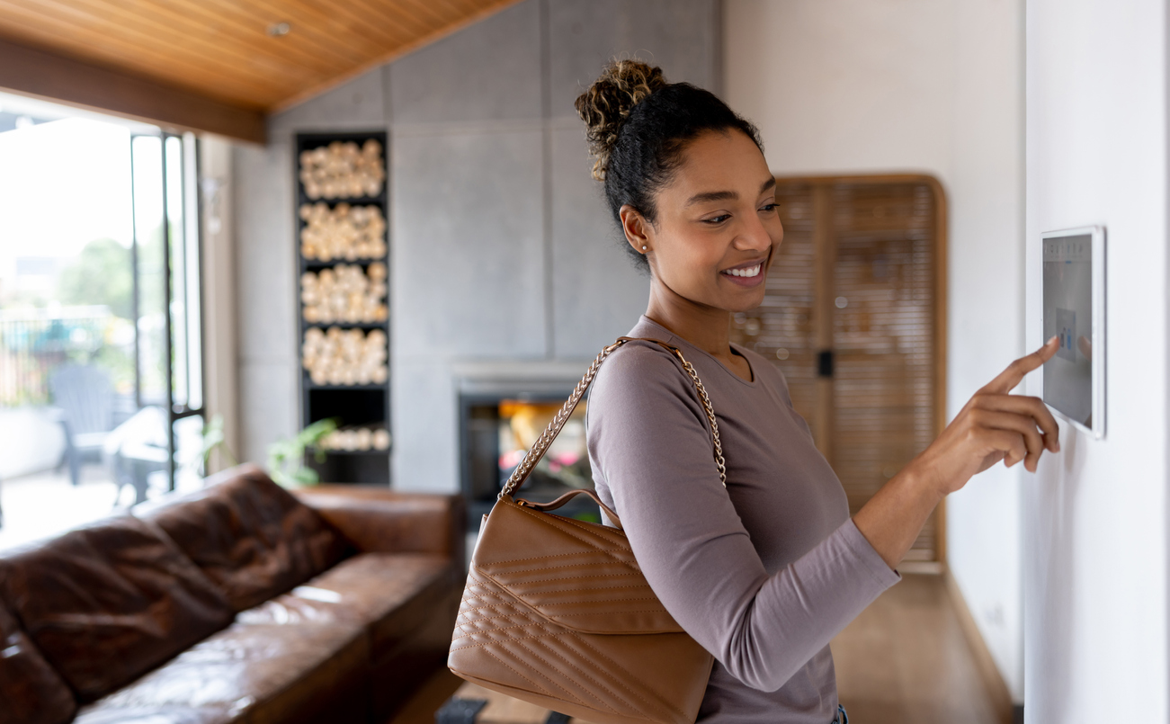 A woman activating the alarm while leaving her smart home using an automated system.