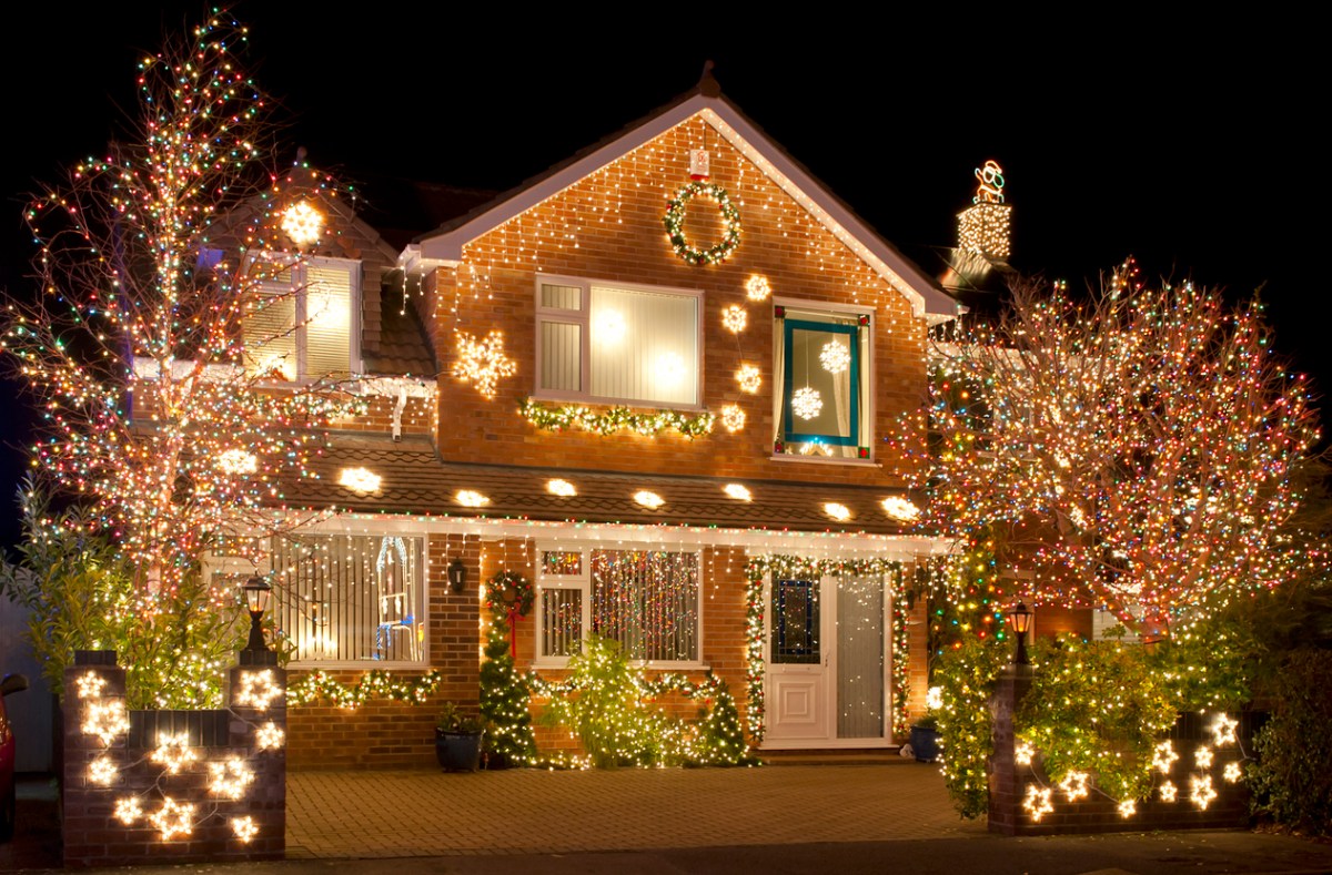 Brick house covered in holiday wreaths and lights.