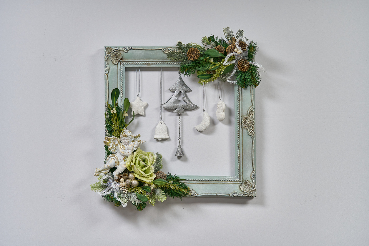 Christmas-ornaments-are-framed-in-a-sage-ornate-photo-frame-with-evergreen-accents.