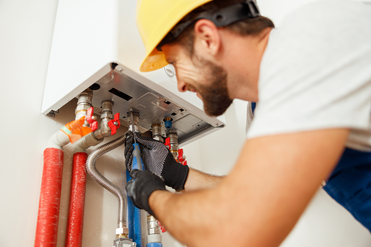 Closeup of plumber using screwdriver while fixing water heater.