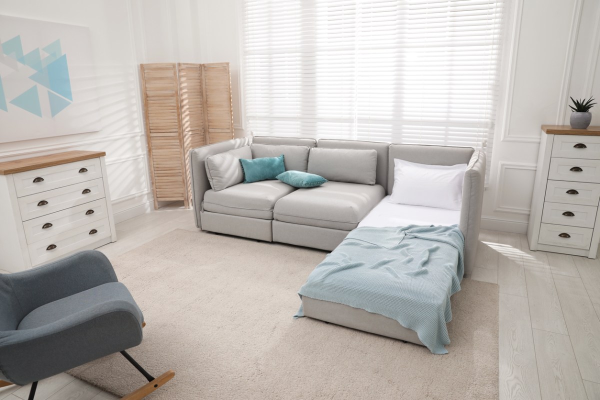 A-guest-room-in-beige-and-blue-decor-has-a-sofa-with-a-guest-sleeper-on-one-end.