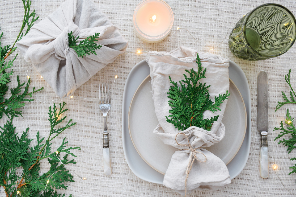 Sprigs-of-evergreen-adorn-a-place-setting-with-white-linens-and-small-twinkly-litghts.